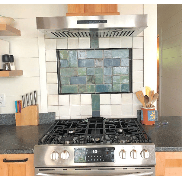 Propane gas stove with range hood and tiled backsplash.
