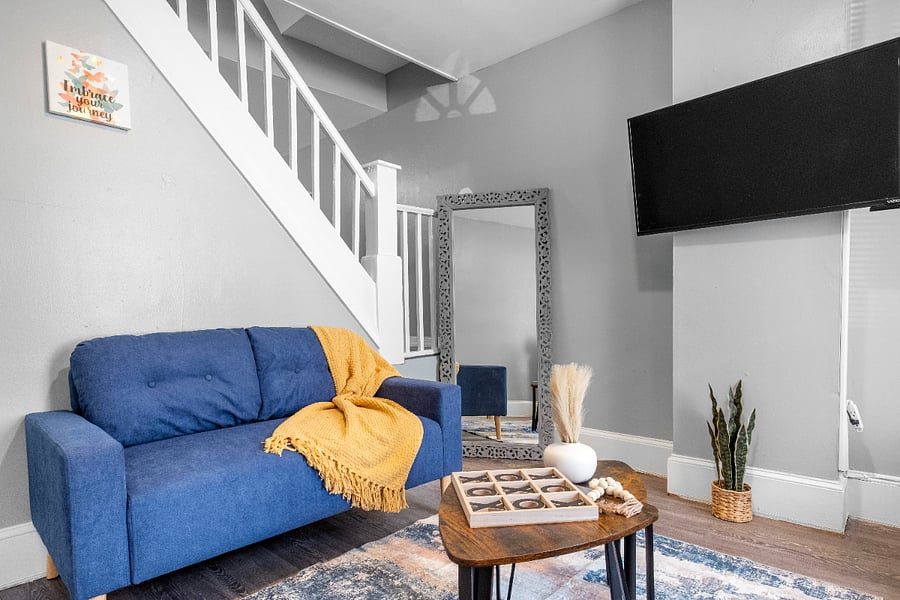A modern apartment living room with one long sofa, two small sofas, a tea table, and a wall-mounted flatscreen TV offers a stylish and comfortable space designed for both lively gatherings and relaxed entertainment.