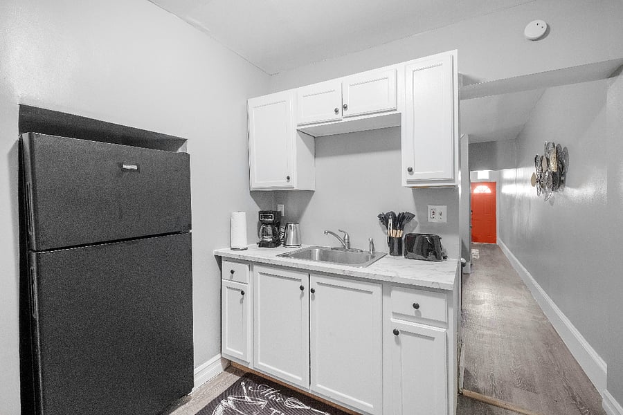 A white kitchen paired with a sleek gray two-door refrigerator combines bright, clean aesthetics with modern metallic accents, creating a stylish and functional culinary space.
