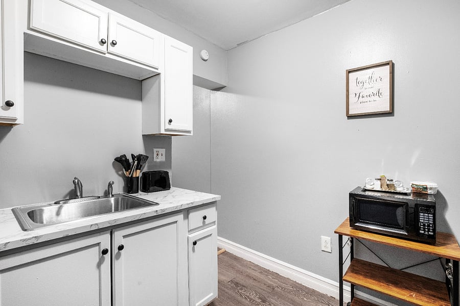 A white kitchen paired with a sleek gray two-door refrigerator combines bright, clean aesthetics with modern metallic accents, creating a stylish and functional culinary space.