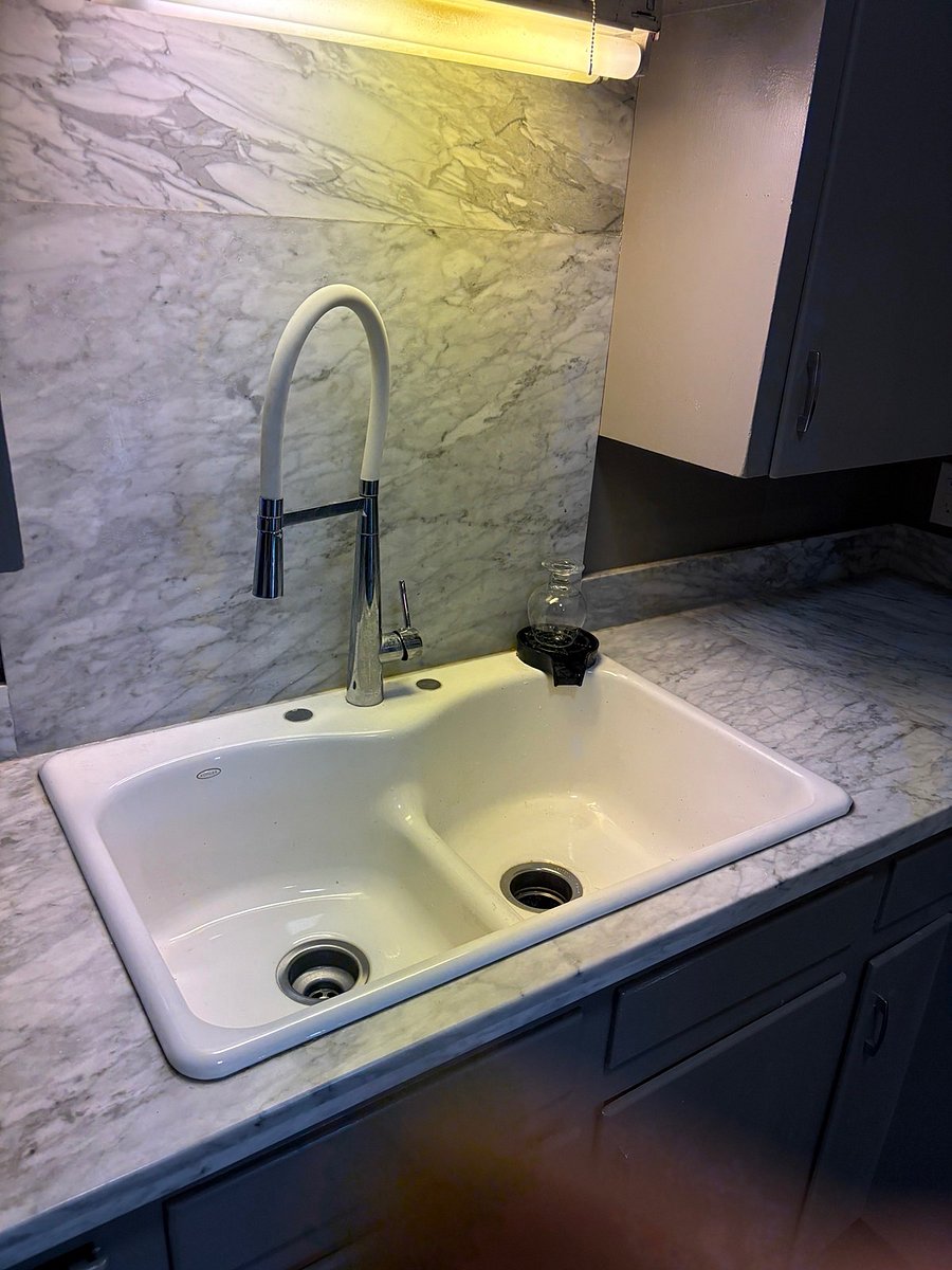 Lovely farm style sink features designer faucet and bartender glass cleaning sprayer (the black circle on the sink trim).