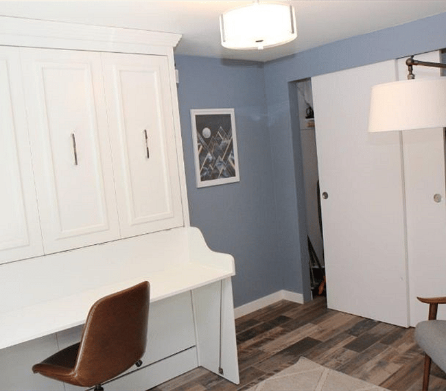 This is the second bedroom on the ground floor, currently shown used a den/office. There is a Murphy bed enclosed in the tall white built-in on the left.