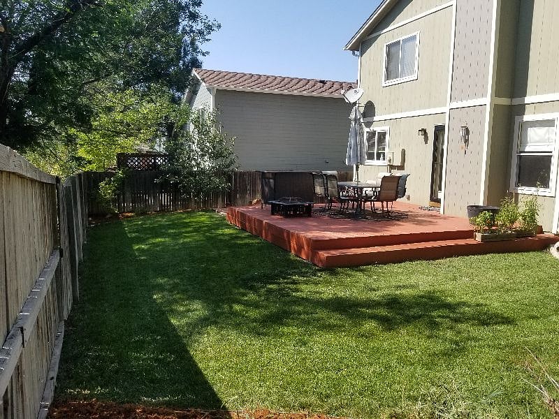 A full backyard with patio, umbrella, and firepit