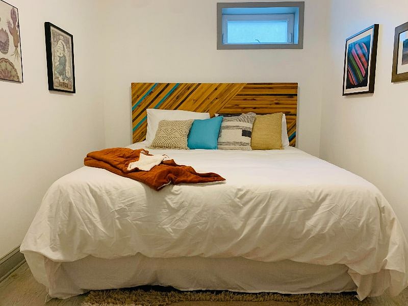 King-size bed with one of a kind headboard and art prints. Bedroom has walk-in closet