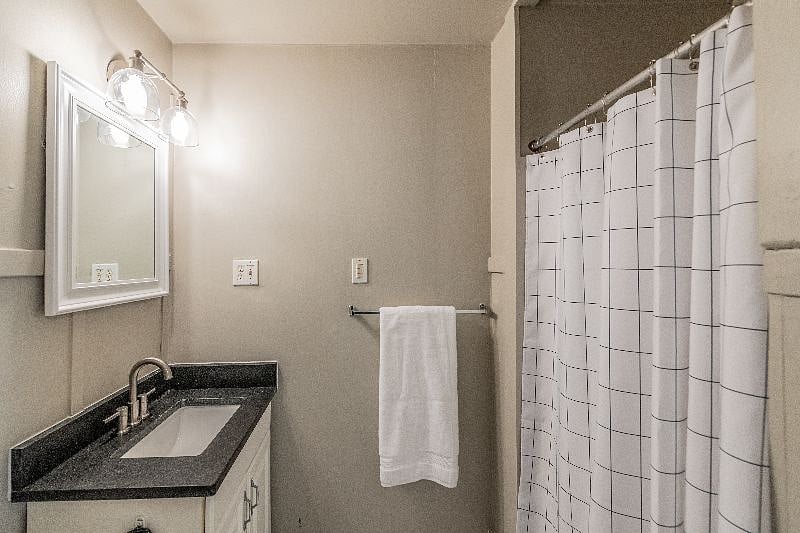 Bathroom with granite sink, upgraded tile flooring and fixtures, rainfall showerhead