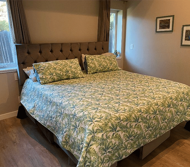 Quiet bedroom with king size bed, blackout curtains, high ceilings with ceiling fan.