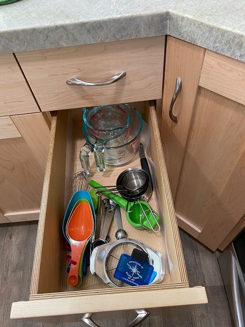 Kitchen drawer with cooking utensils and measuring cups & spoons, plus Pyrex bowls.
