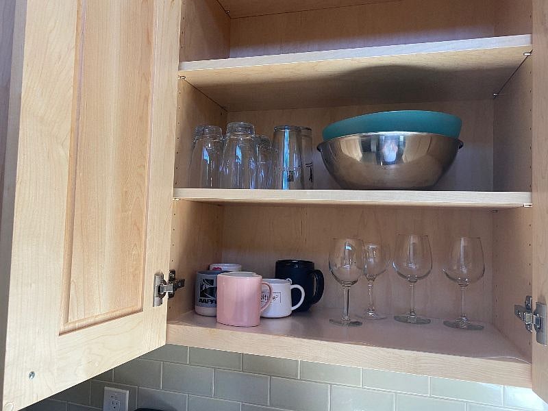 Kitchen cabinet with mixing bowls, glassware and mugs.