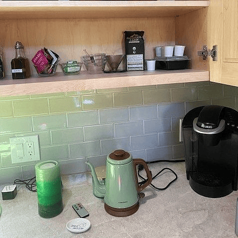 Kitchen counter with Keurig-style coffee maker, electric tea kettle and candle water fountain. Coffee and tea supplies provided in cabinet above.