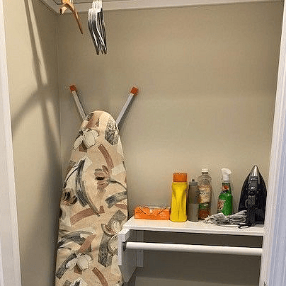Entry closet with rod for clothes or jackets. Iron, ironing board, cleaning supplies and fire extinguisher.