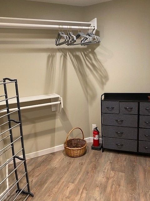 Walk-in closet facing right. Dresser and clothes hanging rods, full-length and half-length.