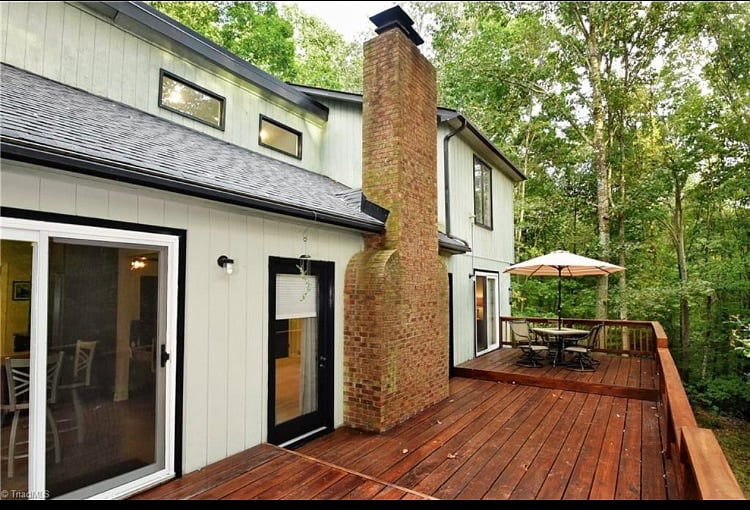 Spacious outdoor deck has outdoor furniture and a second story view of the forest that looks out into treetops