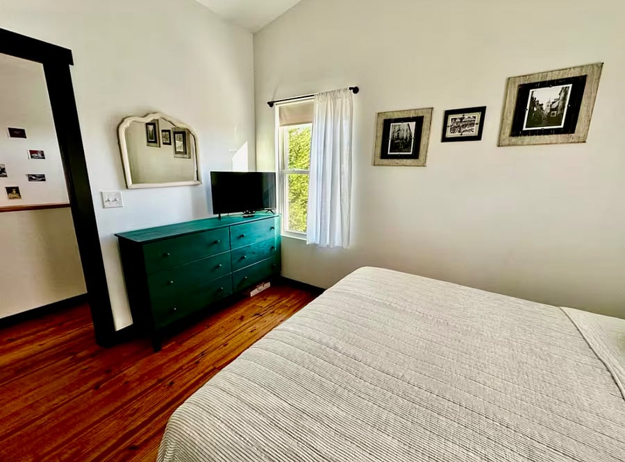 Upstairs bedroom #1 with lofted ceiling, queen-size bed, large closet, nightstand, 6-drawer dresser, ceiling fan, smart TV, and mini-split AC/heating for customized sleeping comfort