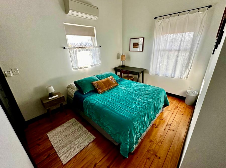 Upstairs bedroom #2 with lofted ceiling, queen-size bed, closet, desk workspace, nightstand, ceiling fan, and mini-split AC/heating for customized sleeping comfort