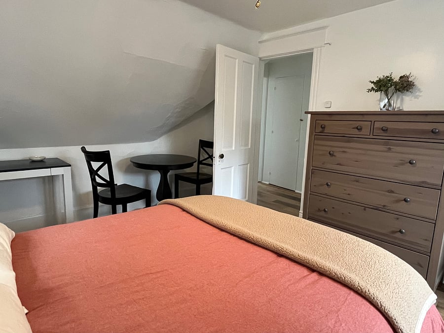 Another view of the bedroom, showing the entrance and seating area.