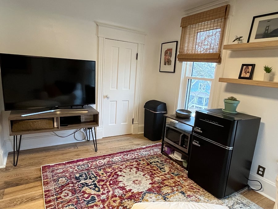 Another view of your living room with mini fridge, microwave, 2 closets, chair, and TV with Roku