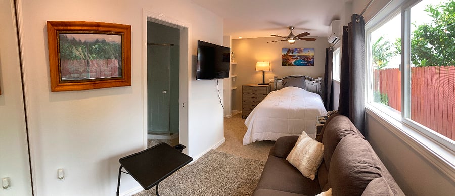 Bedroom with wall mounted 43" smart TV, double bed and separate split AC unit
