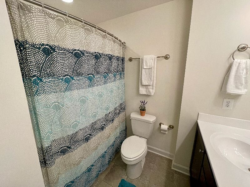The bathroom has a bathtub and shower with curved shower rod, giving it extra space.
