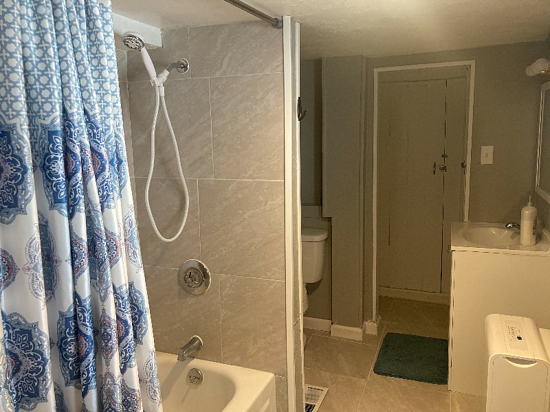 Shower/tub with removable shower head - The house also has a half bath not pictured with toilet, vanity sink, mirror, and storage shelves