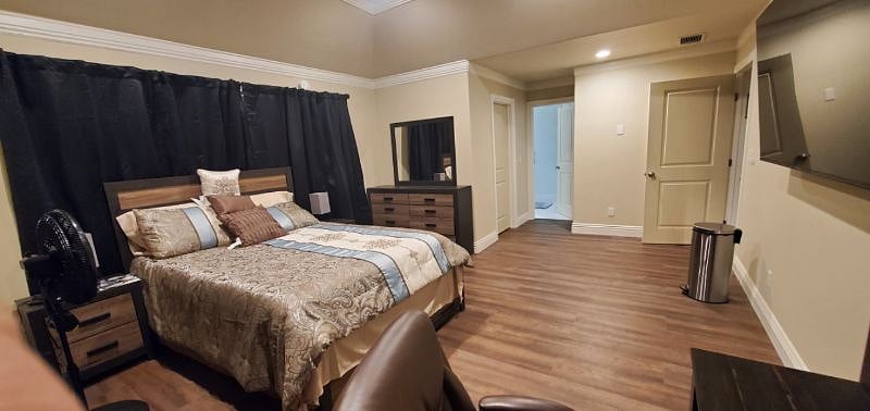Comfortable bed with beautiful linens with dresser and night stand.