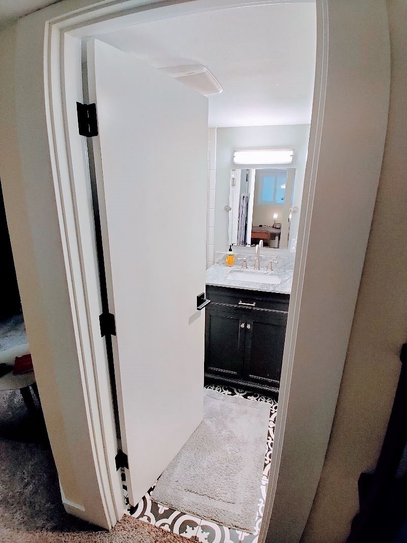 Newly tiled, rain shower head equipped bathroom with tilting mirror and newly installed quiet exhaust fan.