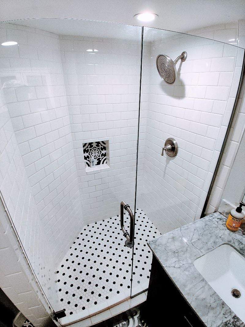 Newly tiled, rain shower head equipped bathroom with tilting mirror and newly installed quiet exhaust fan.
