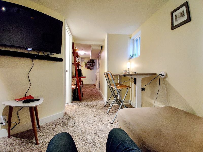View back from smart tv / sound bar equipped living room couch towards the bathroom, kitchen and entryway
