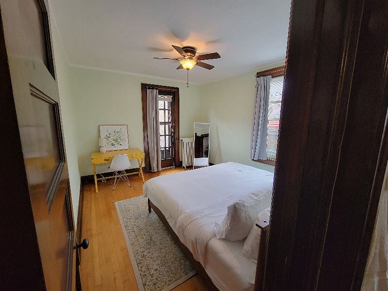 Back bedroom. Overhead fan, full size mirror, king bed, work space and balcony.