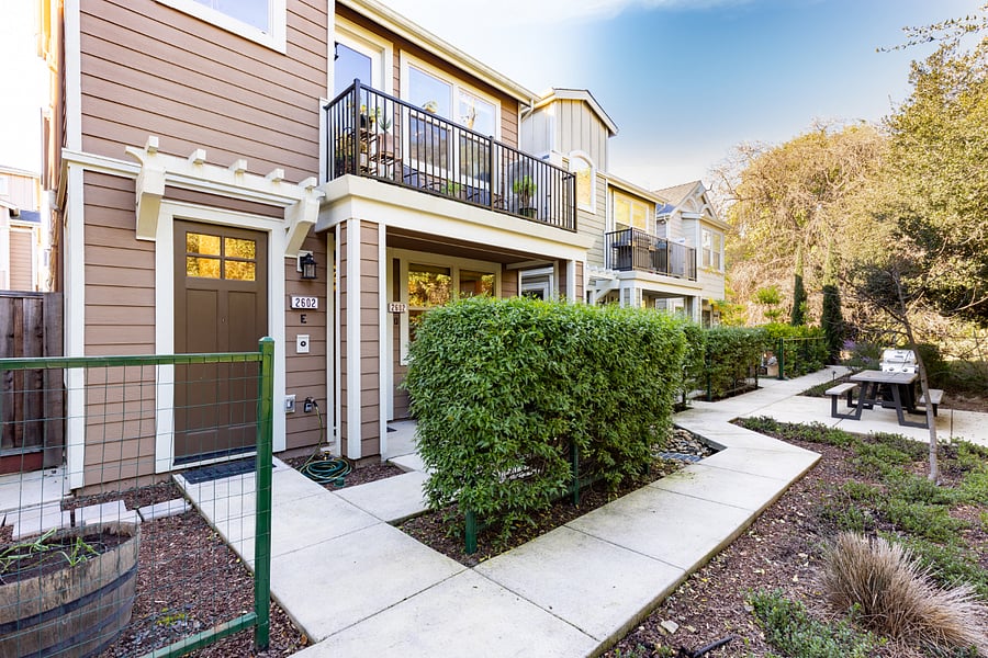 The front door visible is the neighboring unit. The front door of the rental unit is behind the hedge under the balcony. 