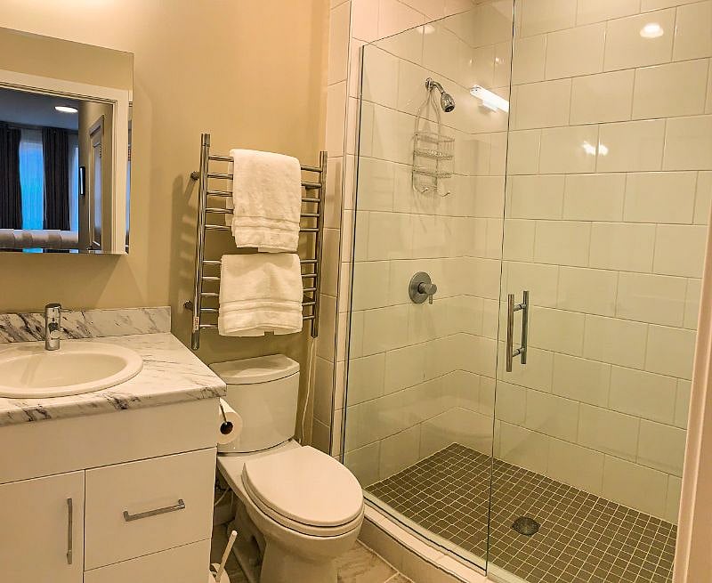 Private bathroom with towel warmer, Toto toilet and glass enclosed tiled shower