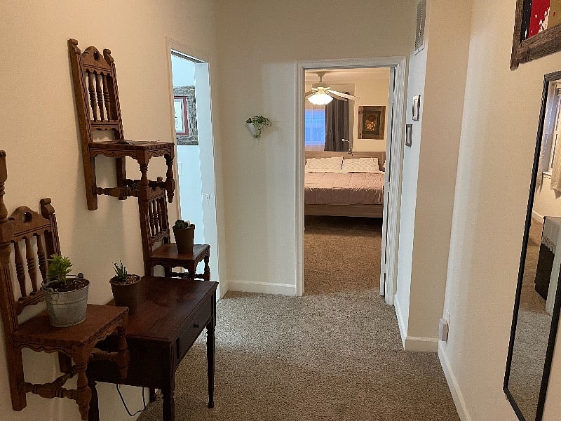 Hallway- view from King room @ top of the stairs. Full bath is on the left, Queen room straight ahead. Full length mirror is to the right, directly across from small chair & plant wall decor.