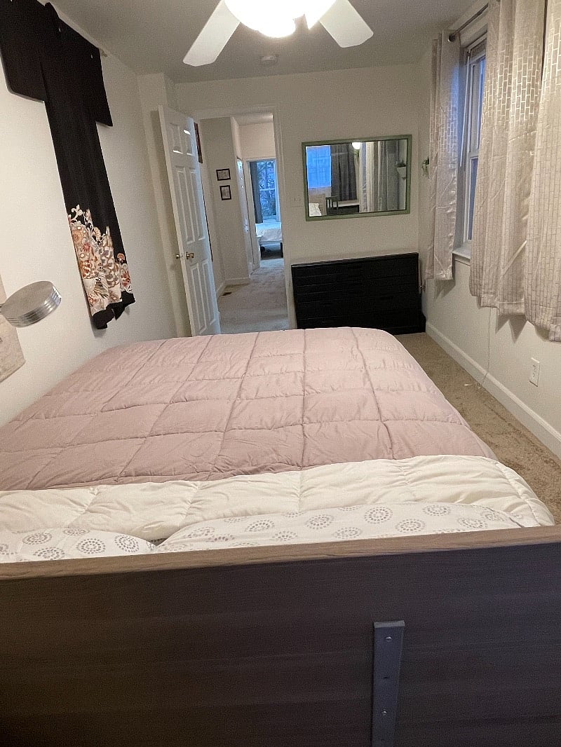 Queen room with dresser, mirror & chair & desk directly behind the bed by the gray curtains.