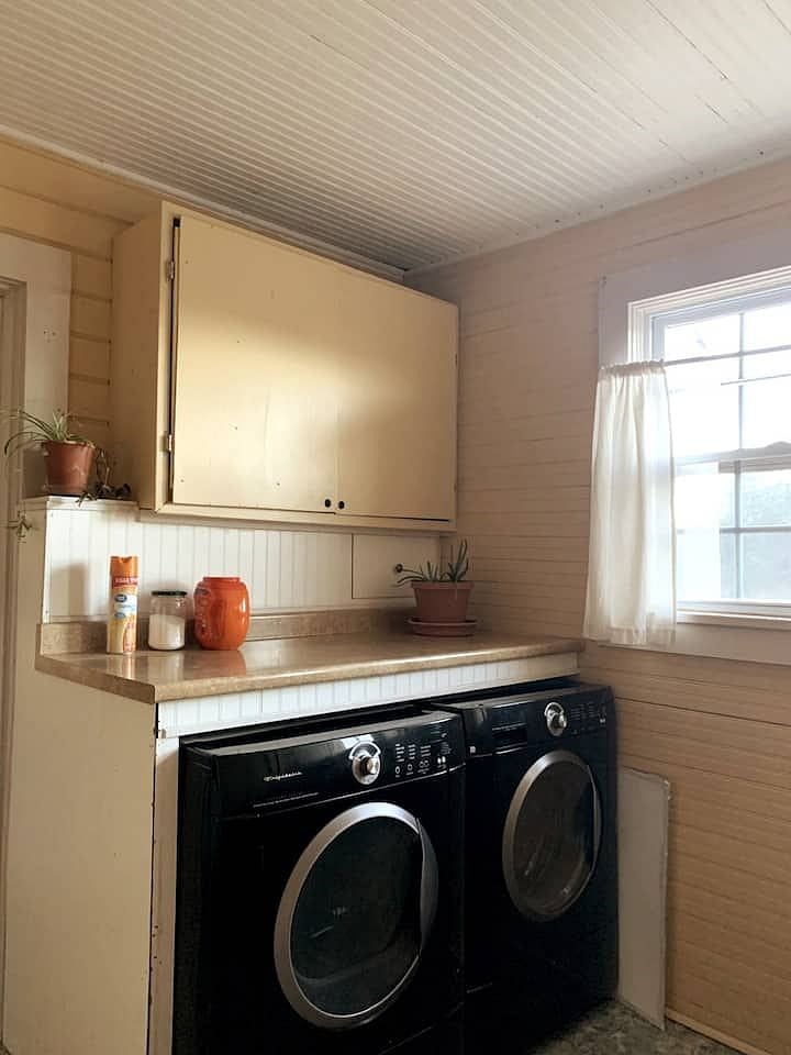 Shared laundry/utility room is located next to the kitchen and includes cleaning supplies and ironing board.