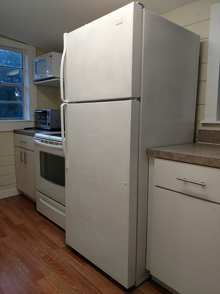 Other side of kitchen with full sized fridge, oven, toaster oven and microwave.