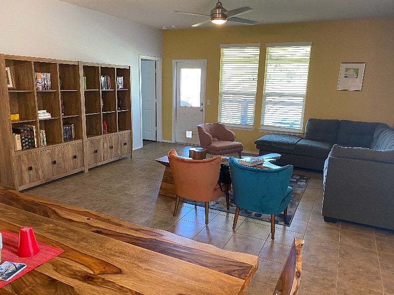 Living area with access to backyard/back porch. Library, L-shaped comfy sectional and additional seating for guests. 