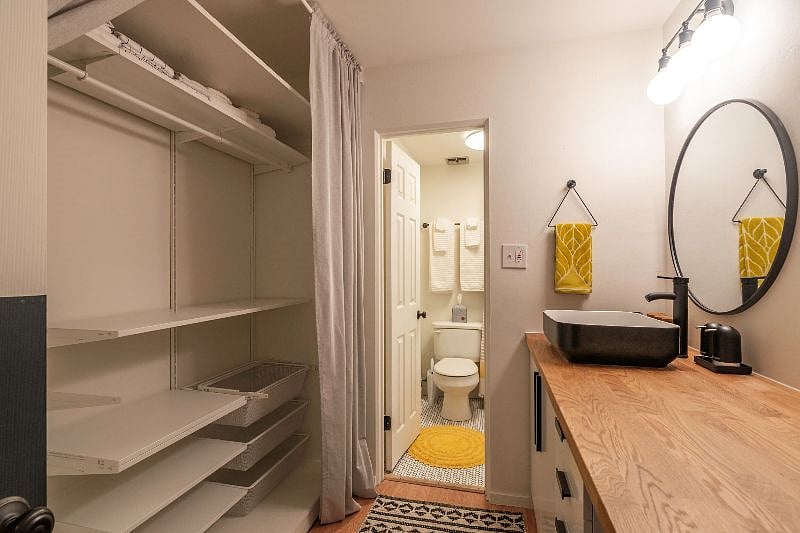 Large closet with plenty of space for hanging items. Extra bed linens and towels on upper shelf.