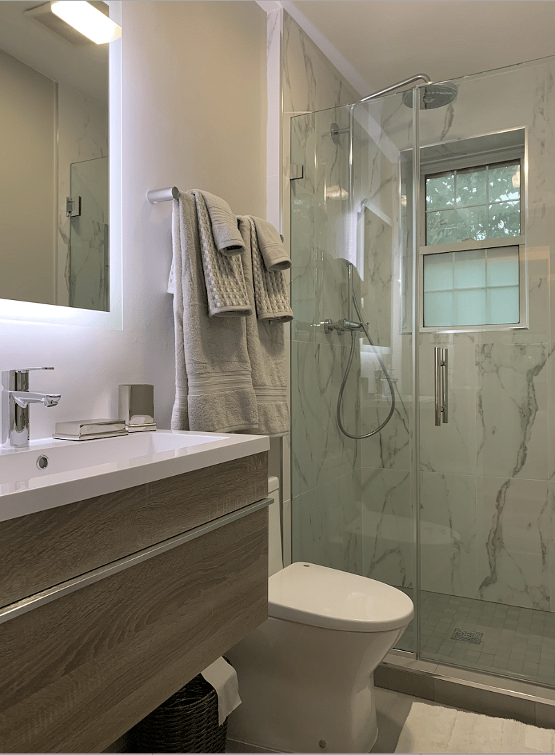 Brand new bathroom with rain and hand-held shower heads, floating vanity, and electric mirror