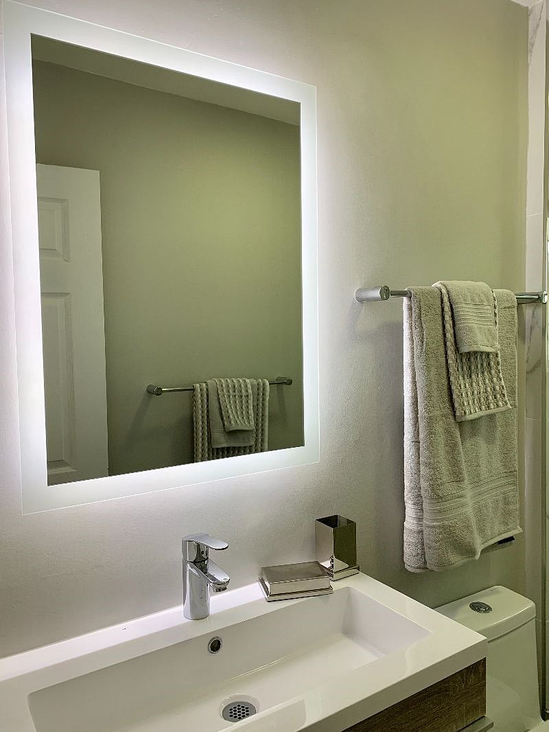 Brand new bathroom with rain and hand-held shower heads, floating vanity, and electric mirror