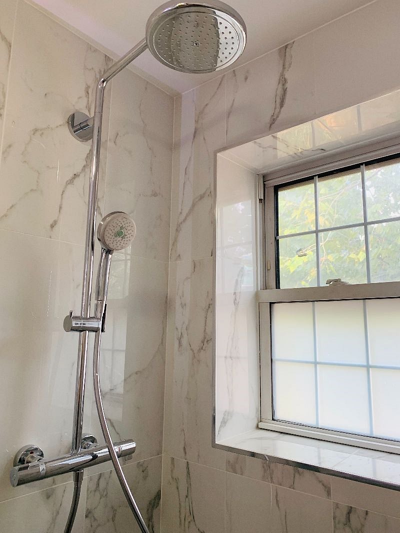Brand new bathroom with rain and hand-held shower heads, floating vanity, and electric mirror