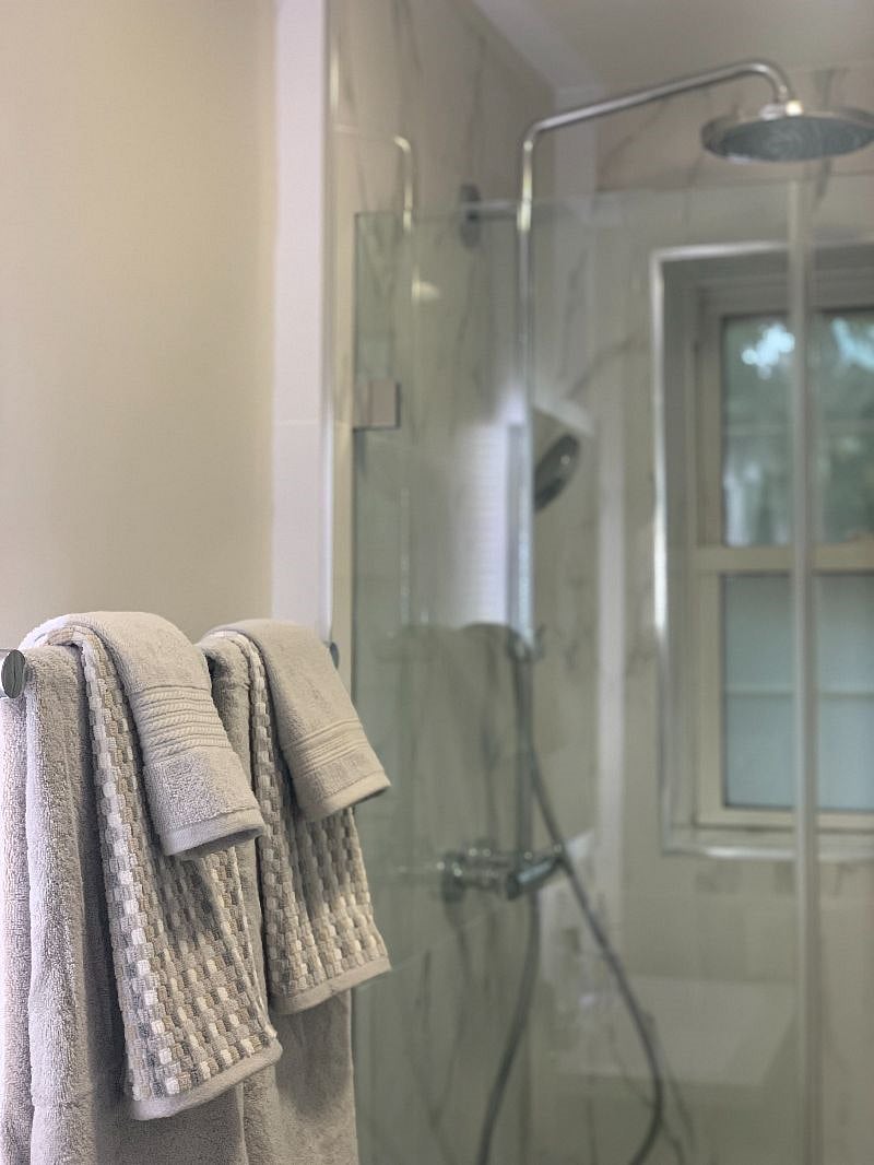 Brand new bathroom with rain and hand-held shower heads, floating vanity, and electric mirror