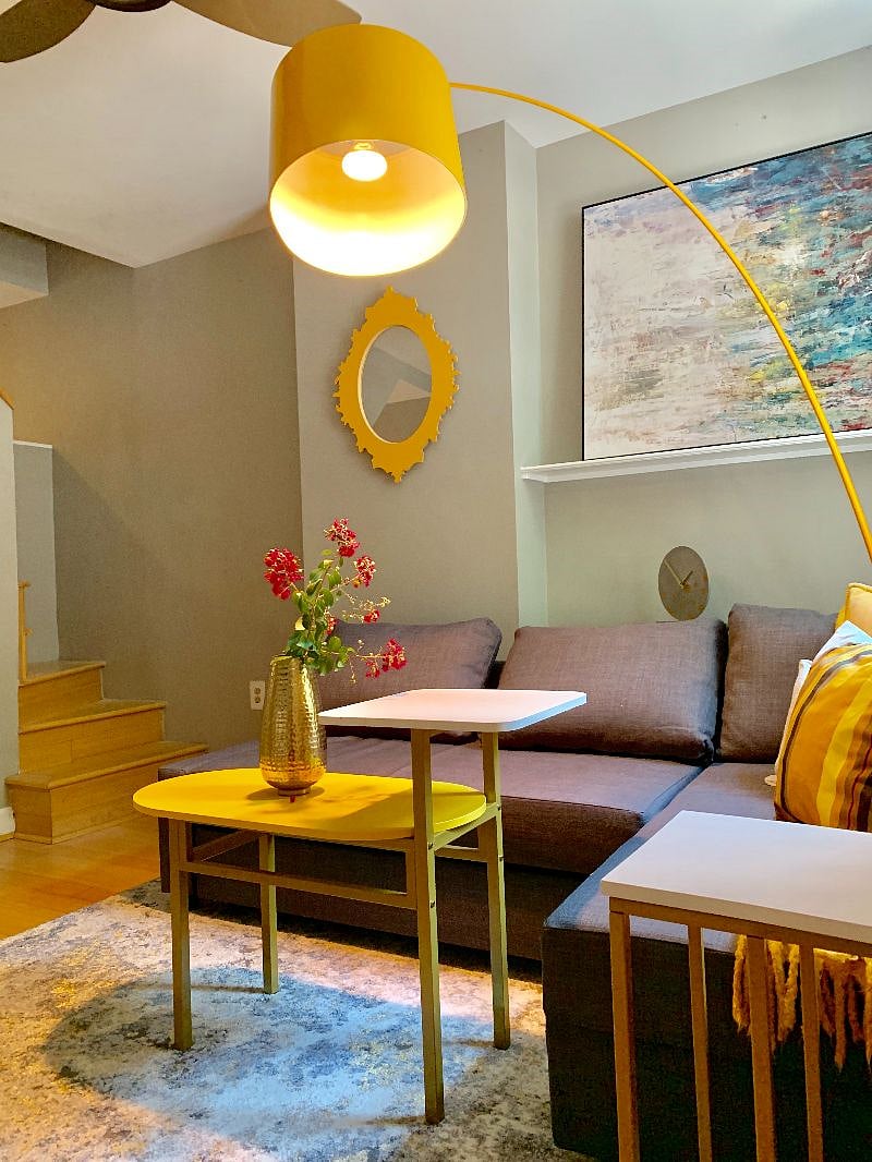 Bright and happy decor in the living room. Stairs in the background lead to the upstairs