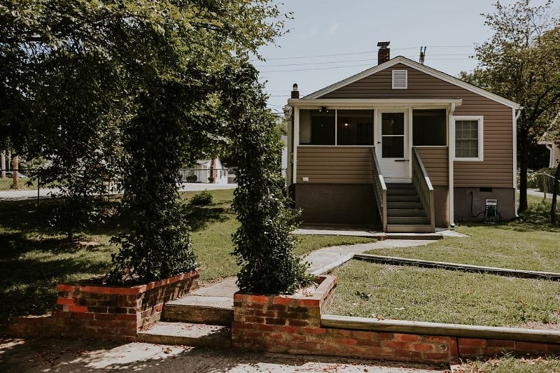 Fenced back yard with steps up to screened porch and back door.