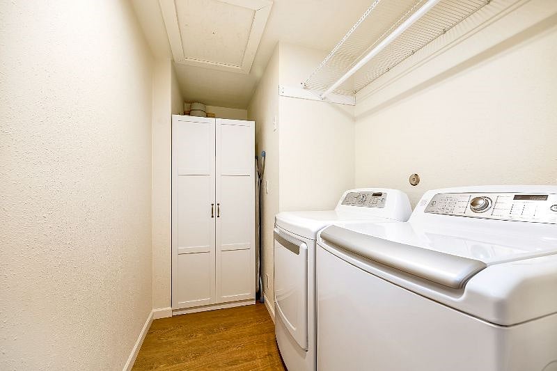 Laundry room with space to hang clothing. Cabinet holds laundry supplies and vacuum.