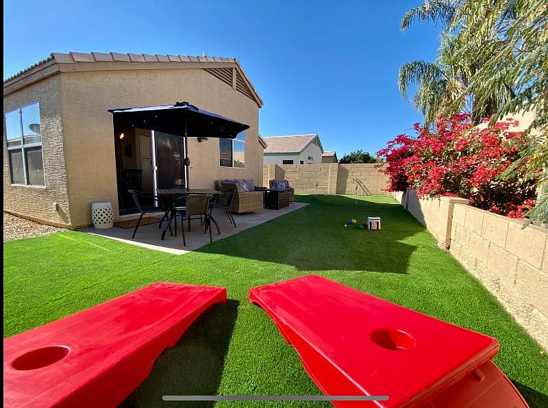 Fully fenced private backyard with putting green, seating with fire-table, and table for outdoor dining.