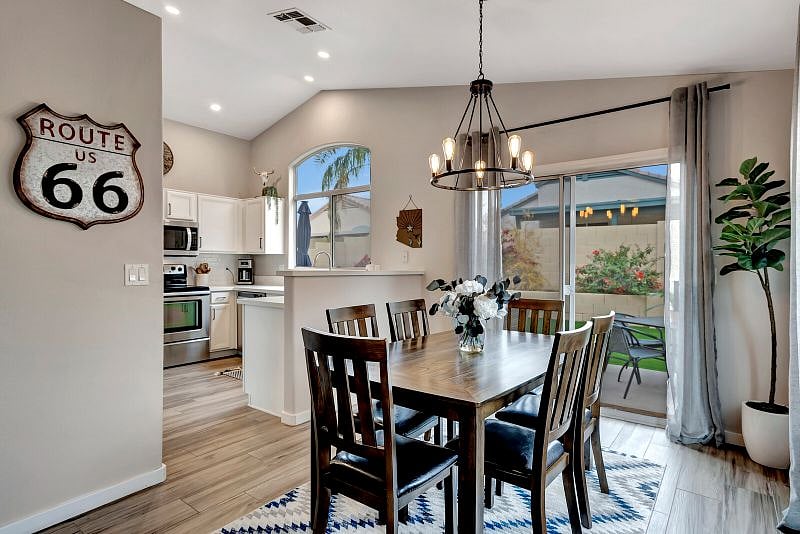 Dining area for 6 features farmhouse chandelier, big windows and slider to the backyard.