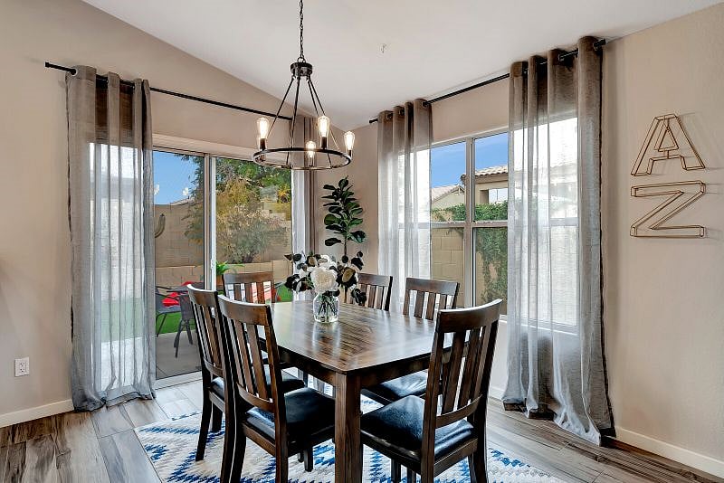 Dining area for 6 features farmhouse chandelier, big windows and slider to the backyard.