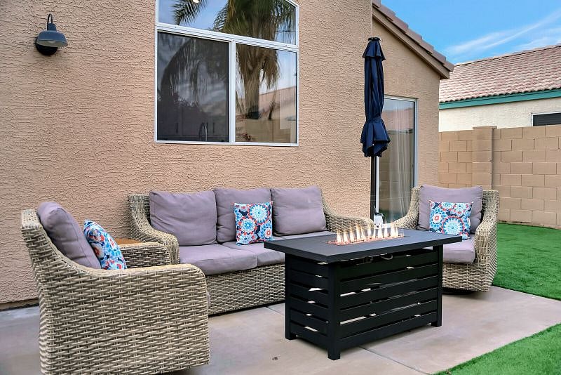 Fully fenced private backyard with putting green, seating with firetable, and table for outdoor dining.