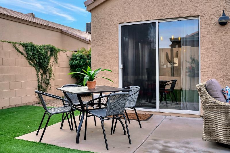 Fully fenced private backyard with putting green, seating with firetable, and table for outdoor dining.