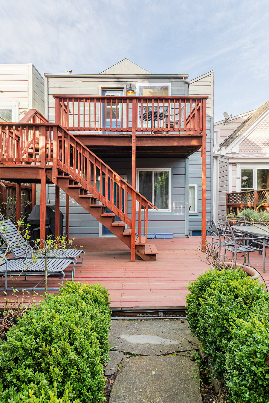 Chaise lounges and a dining area in the landscaped garden. Lower deck is shared with lower unit tenants. Lo