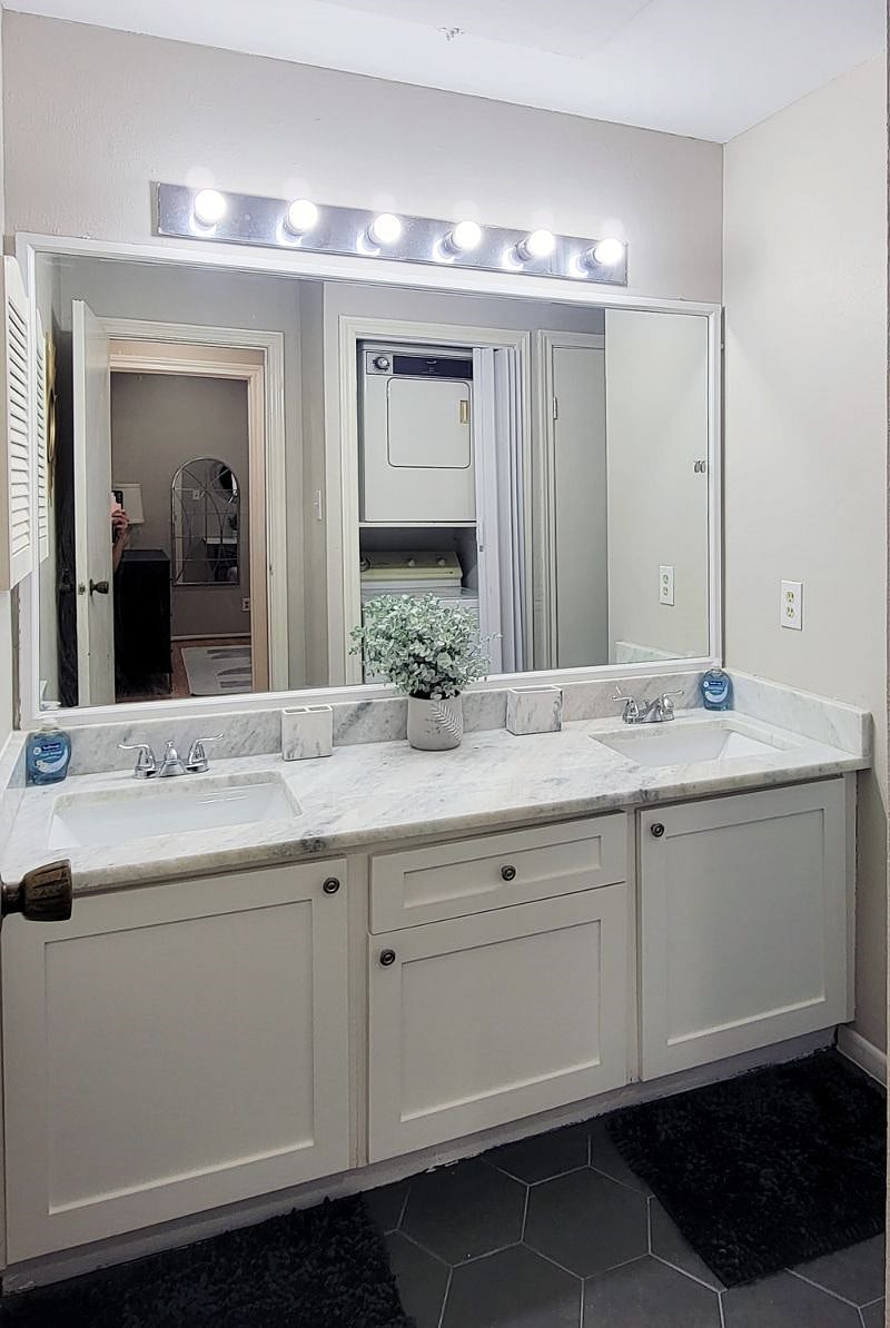 Primary bathroom with updated double sink vanity, quartz counter top, and washer / dryer (old washer and dryer shown in this picture; new washer and dryer installed in February 2022)